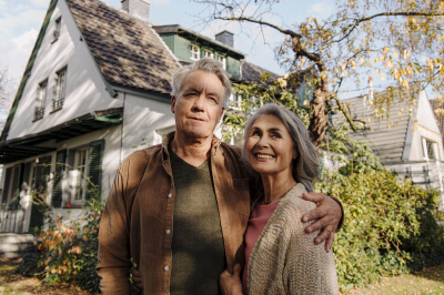 Couple in front of suburban home considers their cash-out refinance home equity.