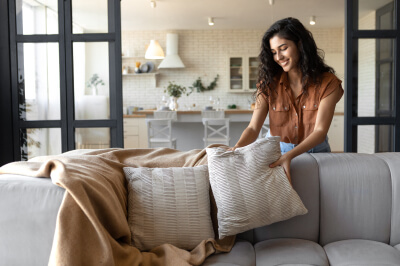 Woman declutters her living room pillows using a checklist on how to declutter her home.