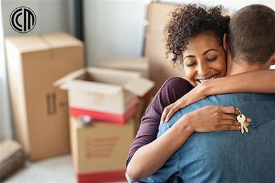 Couple hugging among moving boxes, symbolizing a fresh start made possible by down payment assistance.