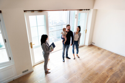 Couple and child tour home for sale during open house with real estate agent.