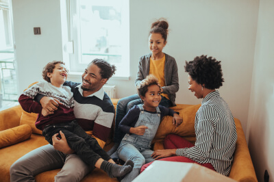 Home buyer Family sits around together on couch in their new home.