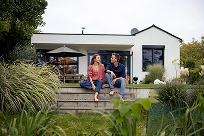 A couple sitting on their porch discussing when mortgage rates will go down & their mortgage refinance options.