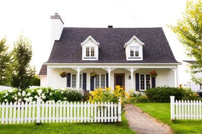 A two-story white house with a vibrant garden exemplifies homeownership and the considerations for the average down payment on a house.