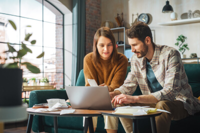 Couple in living room is calculating the percent of their net income that should go to a mortgage.